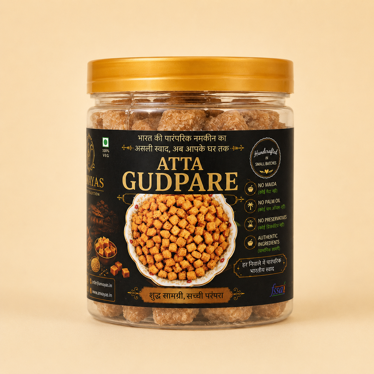 A jar of Atta Gudpare (flourless chickpea snacks) by the brand Kala Kala, featuring a black label with gold lettering and a gold lid, set against a solid beige background.