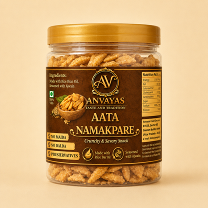 A jar of Anvayas Aata Namakpare crunchy and savory snack, featuring a gold lid and a dark brown label with product details, set against a solid beige background.